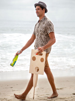 Man walking on the beach holding Goulburn portable beach table in beach blonde color