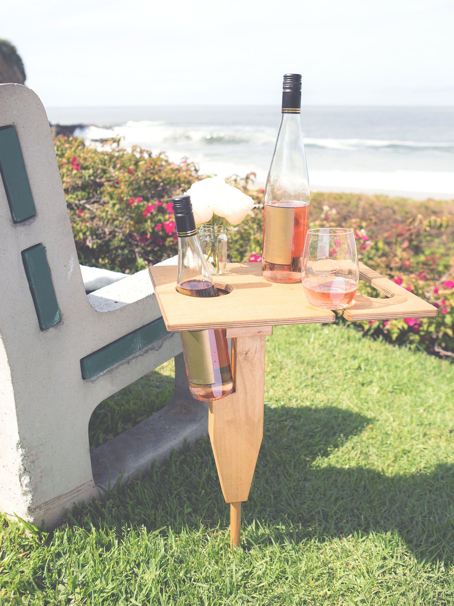 Murray portable beach table in naturally sunkissed color unfolded standing up in grass at park with refreshment drinks